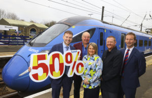 Dennis Fancett, Cllr Richard Wearmouth, Martijn Gilbert and 2 further people from Visit England holding a placard saying 50% growth in front of a Lumo train at Morpeth station